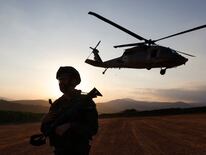 Un soldado israelí mira el horizonte mientras un helicóptero despega. (Photo by Jalaa MAREY / AFP)